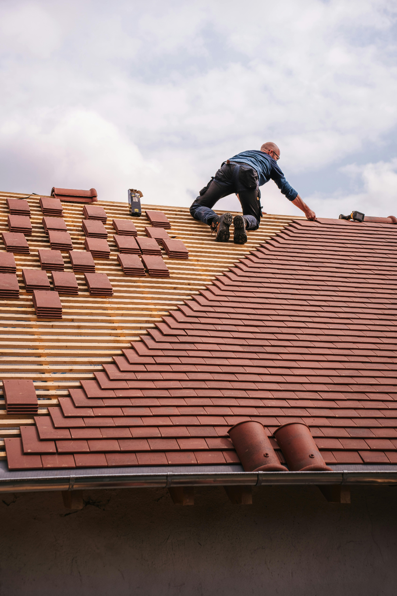 Roofing contractor installing tile roof shingles in progress